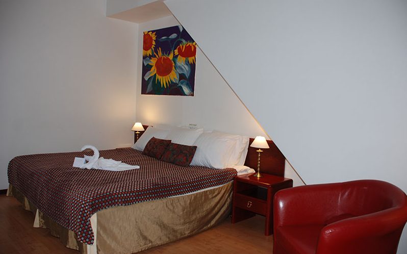 Double room under a sloping ceiling with a red armchair
