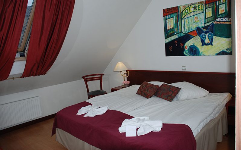 Double bed under a sloping ceiling with a red bedspread